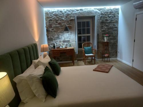 - une chambre avec un grand lit et un mur en pierre dans l'établissement Quinta Casa Do Quintal, à Lamego
