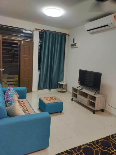 een woonkamer met een blauwe bank en een tv bij BEACHWALK HOMESTAY in Kuala Kurau