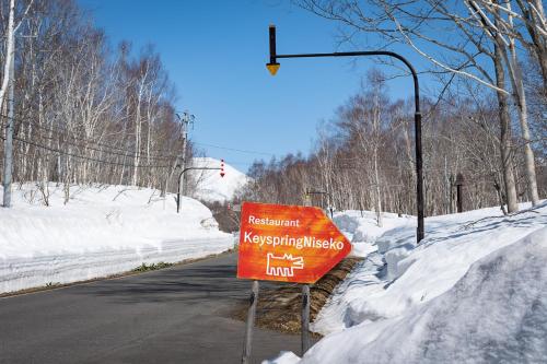 a sign on the side of a road in the snow at Niseko HyKrots IKIGAI Village in Rankoshi