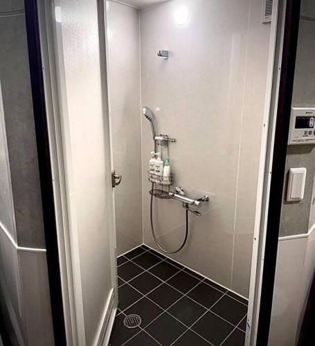 a shower in a bathroom with a black tile floor at とぅも～る in Ishigaki Island