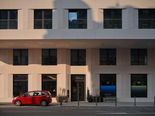 um carro vermelho estacionado em frente a um edifício em Adina Apartment Hotel Wiesbaden em Wiesbaden