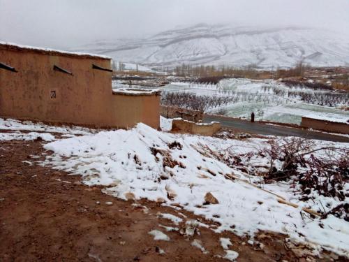 a building with snow on the ground next to a mountain at Ait daoud ait hani tinghir 