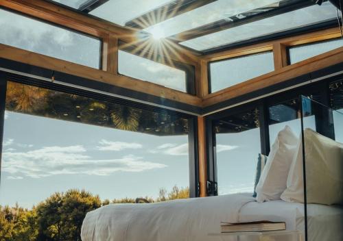 a bedroom with large glass windows and a bed at Korimako PurePod in Scargill