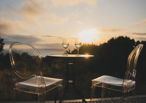 dos copas de vino sentadas en una mesa frente a la puesta de sol en Korimako PurePod, en Scargill