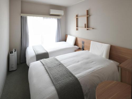 a hotel room with two beds and a window at Vessel Inn Asakusa Tsukuba Express in Tokyo