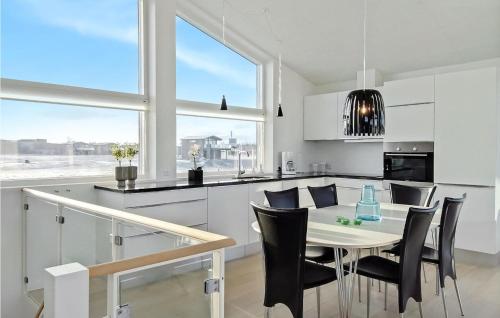 a white kitchen with a dining table and chairs at Holiday Home Kæreng in Frederikshavn