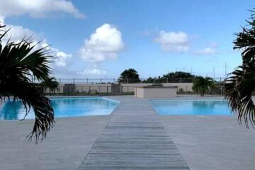 a swimming pool with blue water and palm trees at TiSucrier Orient Bay Ocean Front in Orient Bay