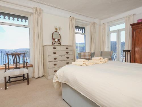a bedroom with a bed and a dresser and windows at Edinburgh House in Salcombe