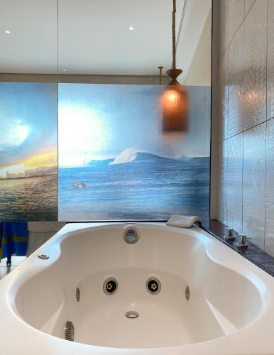a bath tub in a bathroom with a painting at Pousada Ubuntu in Ubatuba