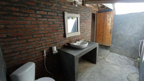 ein Badezimmer mit einem Waschbecken und einer Ziegelwand in der Unterkunft Hakiki Inn Bungalows in Tetebatu