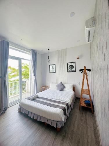 a bedroom with a large bed and a large window at Sele House in Ha Tien
