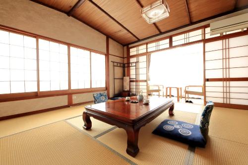 a living room with a table and chairs and windows at Fujimiya in Toyooka