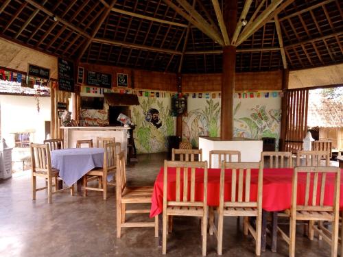 ein Esszimmer mit einem Tisch, Stühlen und einer Wand in der Unterkunft Hakiki Inn Bungalows in Tetebatu