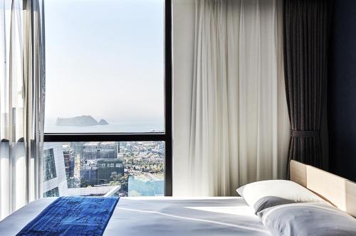 1 dormitorio con cama y ventana grande en Jeju Pureun Hotel en Seogwipo