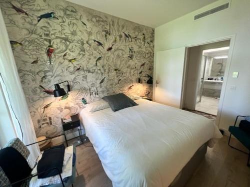 une chambre avec un grand lit blanc avec un papier peint fleuri dans l'établissement Splendide appartement avec piscine et jardin face à la mer - FR-1-726-2, à La Croix-Valmer