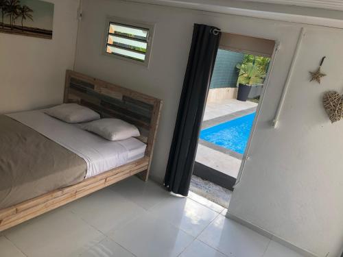 a bedroom with a bed and a door leading to a pool at Villa bassin bleu in Gourbeyre