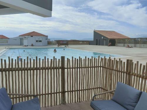 - une piscine avec 2 chaises et une clôture en bois dans l'établissement T2 avec Terrasse, Vue Port, Parking Privé, Espace Aquatique, et Plus - 4 Couchages - FR-1-195-99, au Barcarès