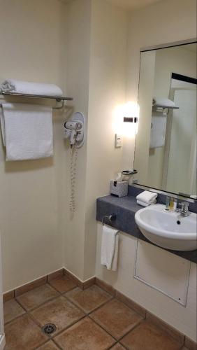 a bathroom with a sink and a mirror at City of Sails Motel in Auckland