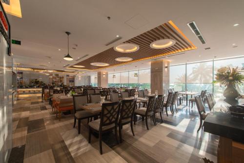 a dining room with tables and chairs and windows at Navada Beach Hotel in Nha Trang