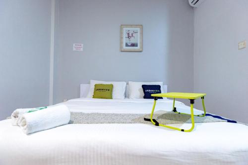 a bedroom with two beds and a yellow table at Urbanview Hotel Crystal Nagoya Batam by RedDoorz in Batam Center