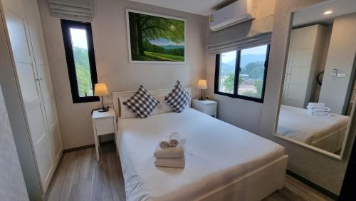 a bedroom with a large white bed with towels on it at D4 The Title Residencies Naiyang Two Bedroom Phuket in Nai Yang Beach