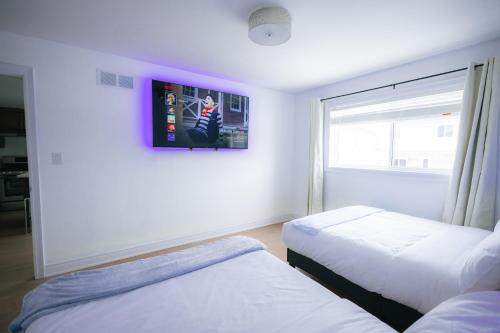 Habitación con 2 camas y TV en la pared. en 5 BEDS On The Rapids - 5 Mins To The Falls, en Niagara Falls