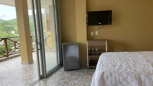 a bedroom with a bed and a tv and a balcony at Cabañas Paraiso in Taganga