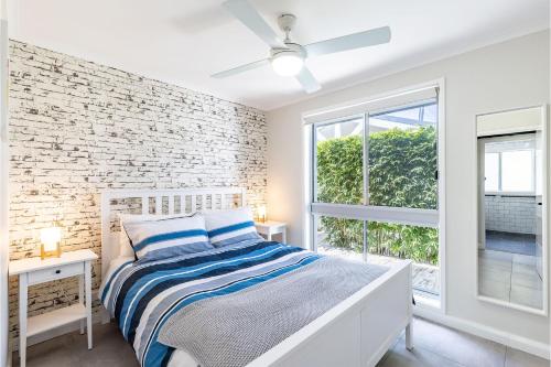 アンナ・ベイにあるSeabreeze 18 Abel Place fantastic holiday house on the beachの白いベッドルーム(ベッド1台付)とレンガの壁