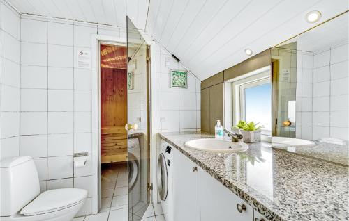 a white bathroom with a toilet and a sink at Awesome Home In Ringkbing With 4 Bedrooms, Sauna And Indoor Swimming Pool in Søndervig