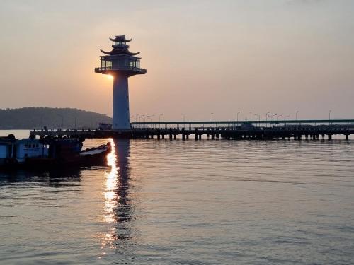 a lighthouse on the water next to a pier at Sawasdee Sichang Resort in Ban Tha Thewawong