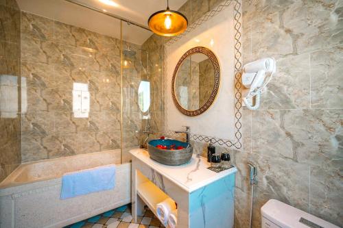uma casa de banho com um chuveiro, um lavatório e uma banheira em Hoi An Babylon Riverside Hotel & Spa em Hoi An