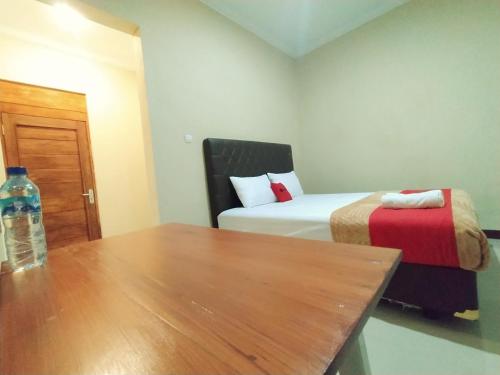 a room with a bed and a table with a bottle of water at RedDoorz near Prawirotaman Yogyakarta in Yogyakarta