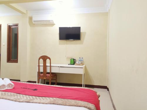 a room with a bed and a desk and a tv at RedDoorz near Prawirotaman Yogyakarta in Yogyakarta
