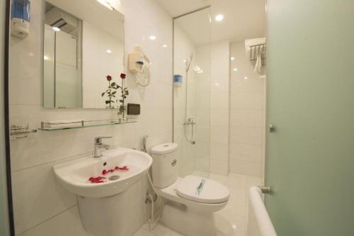 a white bathroom with a toilet and a sink at Hanoi Holiday Hotel in Hanoi