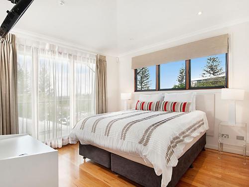 a white bedroom with a large bed and windows at 1 20 Kingfisher Drive Peregian Beach in Peregian Beach