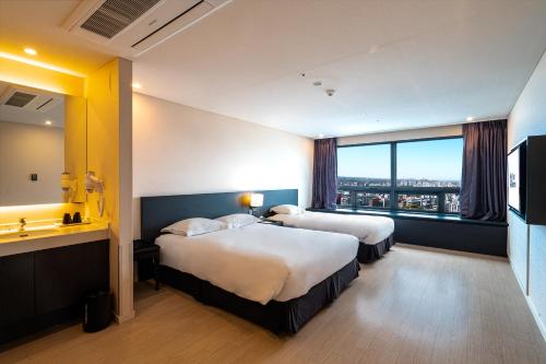 a hotel room with two beds and a large window at Best Western Jeju Hotel in Jeju