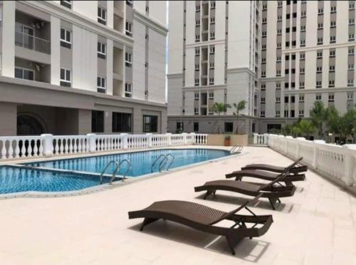 a swimming pool with benches in a building at IMPERIAL PLACE - NATURAL POEM View đẹp - hồ bơi, gym miễn phí in Ho Chi Minh City
