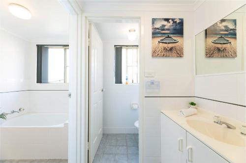 a white bathroom with a tub and a sink at Haven Waters 3 in Forster