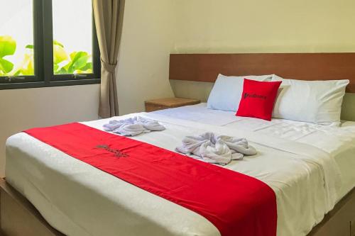 ein Schlafzimmer mit einem roten und weißen Bett mit Handtüchern darauf in der Unterkunft RedDoorz Syariah near Stasiun Madiun 2 in Madiun