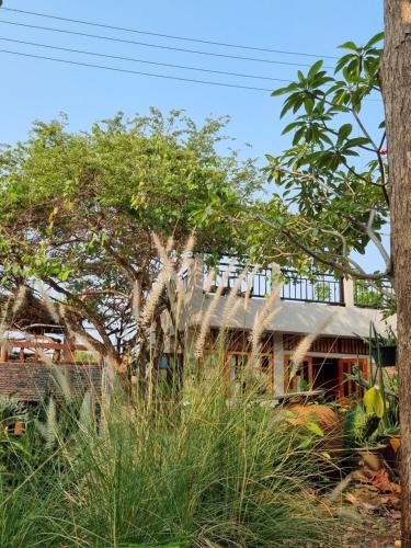 a house with a tree in front of it at Sawasdee Sichang Resort in Ban Tha Thewawong