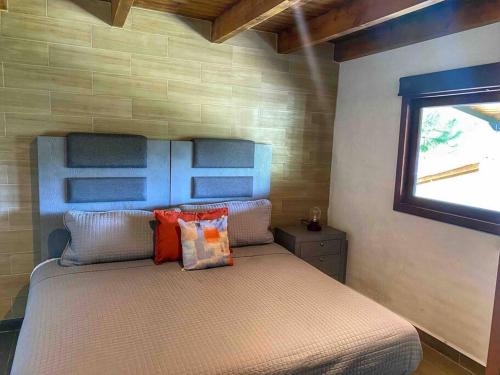 1 dormitorio con cama con almohadas y ventana en Cabaña Familiar 05 en Mazamitla