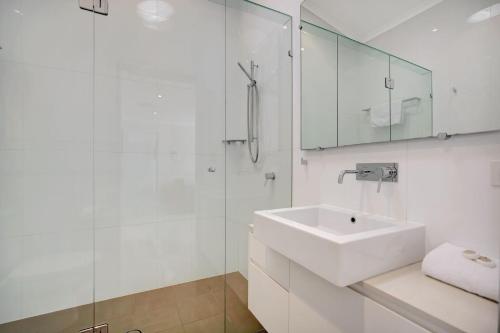 a white bathroom with a sink and a shower at 2 20 Kingfisher Dr Peregian Beach in Peregian Beach