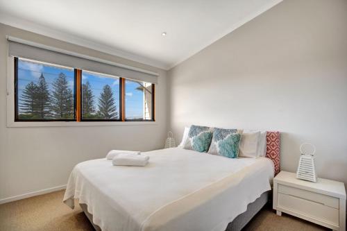 a white bedroom with a large bed and a window at 2 20 Kingfisher Dr Peregian Beach in Peregian Beach