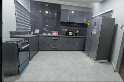 een grote keuken met zwarte kasten en apparaten bij Cozy penthouse ,Accra Ghana in Owuraman