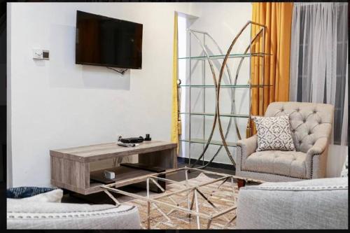 een woonkamer met een tv en een tafel en een stoel bij Cozy penthouse ,Accra Ghana in Owuraman