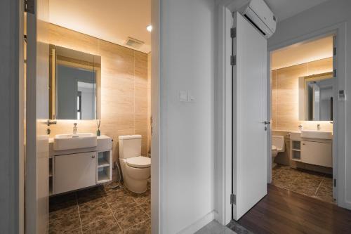 La salle de bains est pourvue de 2 lavabos, de toilettes et de 2 miroirs. dans l'établissement Troy House - Serviced Apartment - DCapitale, à Hanoï