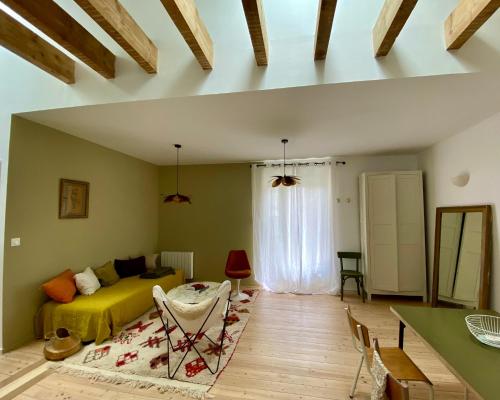 uma sala de estar com uma cama amarela e uma mesa em L’appartement 39 em Lons-le-Saunier