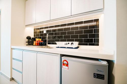 a kitchen with white cabinets and a sink and a dishwasher at Chill Suites Kuala Lumpur in Kuala Lumpur