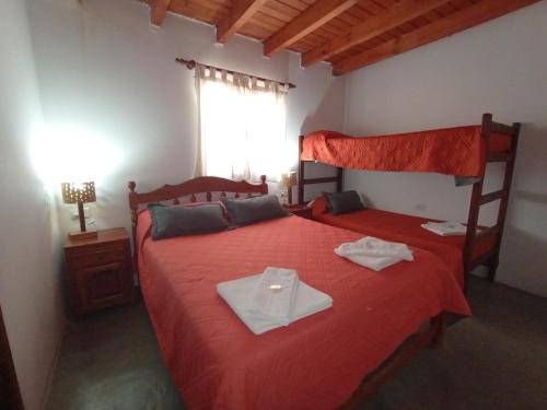 een slaapkamer met 2 bedden met rode lakens en een raam bij EL WICHIKU RECIDENCIAL - RESTO-BAR Facebook Hospedaje El Wichiku- Iruya in Iruya