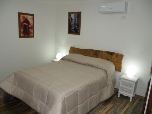 a bedroom with a bed and two pictures on the wall at Dimora Forgione B&B - Pietrelcina in Pietrelcina